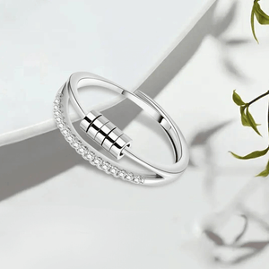 Cubic zirconia silver fidget ring with sliding beads next to a plate on a white surface