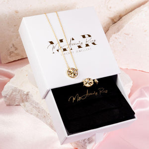 Fidget jewellery necklace and ring set with a star spinning top on a white jewellery box on pink background
