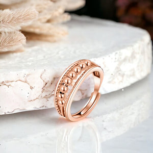 Rose gold worry ring with beads on a marble counter top