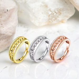 Silver, gold and rose gold worry rings on a marble counter top with a marble background