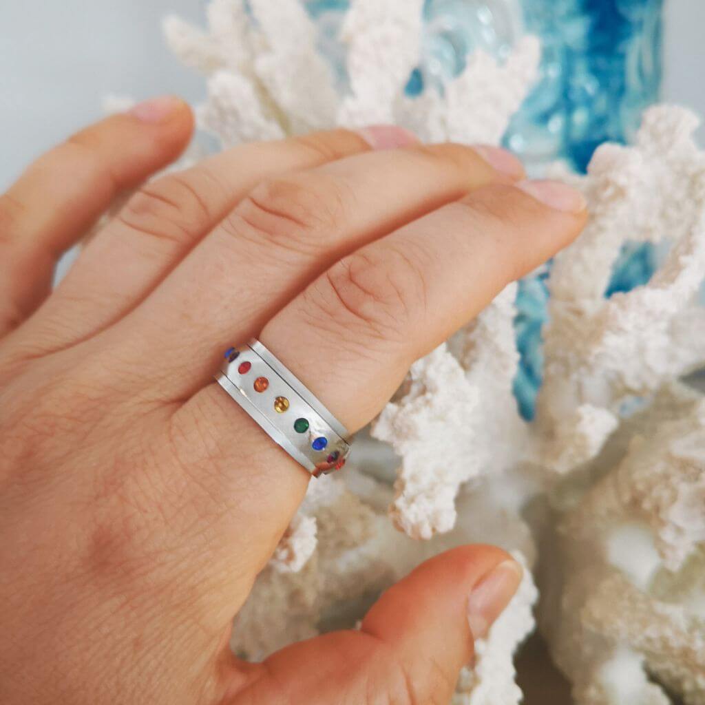 Band fidget ring with multi colored cubic zirconia on white background