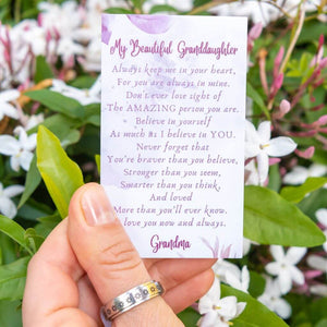 Hand wearing a daisy ring holding a message card for granddaughter