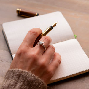 Woman's hand holding a pen wearing a sun fidget ring in Australia