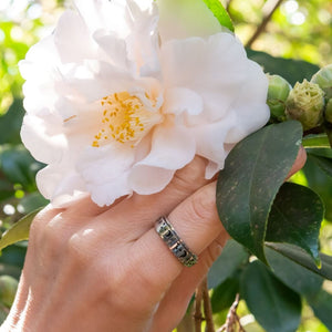 Woman's hand wearing a moon and stars ring next to a white flower