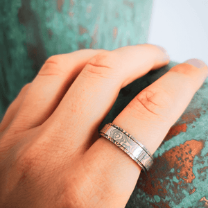 Damascus steel ring on a woman's index finger on turquoise background