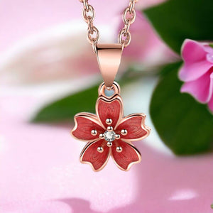Fidget necklace with a cherry blossom pendant on a pink surface and pink fabric in background