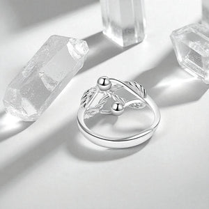 Fidget ring sterling silver with to beads on a grey surface and quartz crystals in background