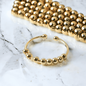 Gold adjustable ring with beads on a marble counter top