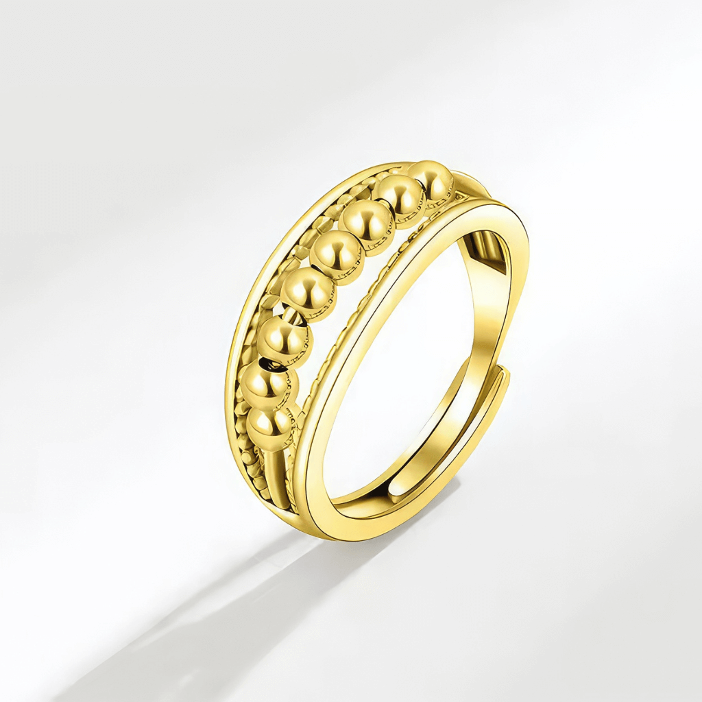 Gold fidget ring with beads on grey background