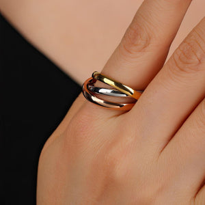 Gold and silver ring on a finger against a neutral background