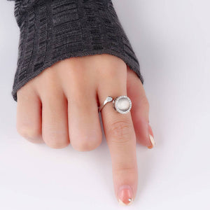 Hand wearing a silver ring with a pearl on a white background