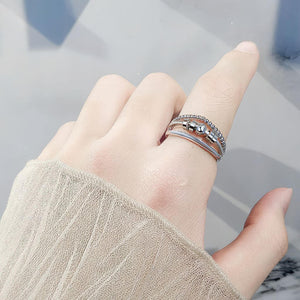 Hand wearing a silver beaded ring with a blurred background