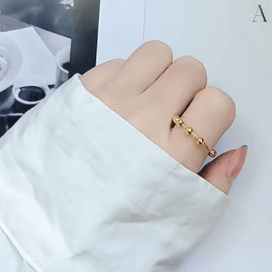 Hand with white sleeve wearing a gold adjustable ring on the index finger