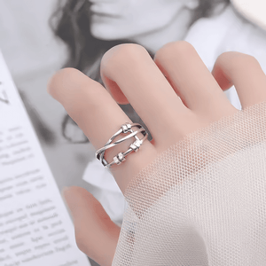 Silver meditation ring on a woman's index finger with a magazine in background