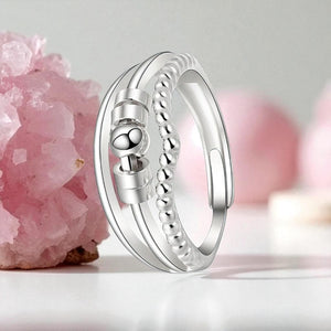 Silver ring  for anxiety with beaded design next to a pink quartz crystal