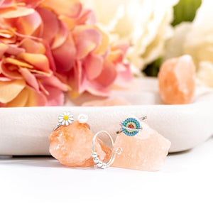 Soothing bundle of 3 silver adjustable rings on pink salt stones with a pink flower background
