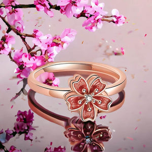 Spinning ring with cherry blossom top on a mirrored surface with cherry flowers in background