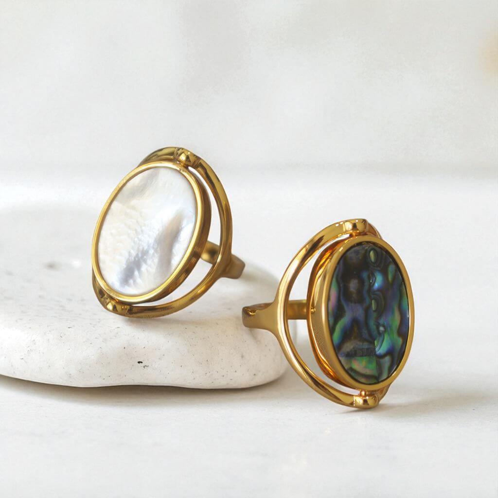 Two gold abalone rings on a white stone