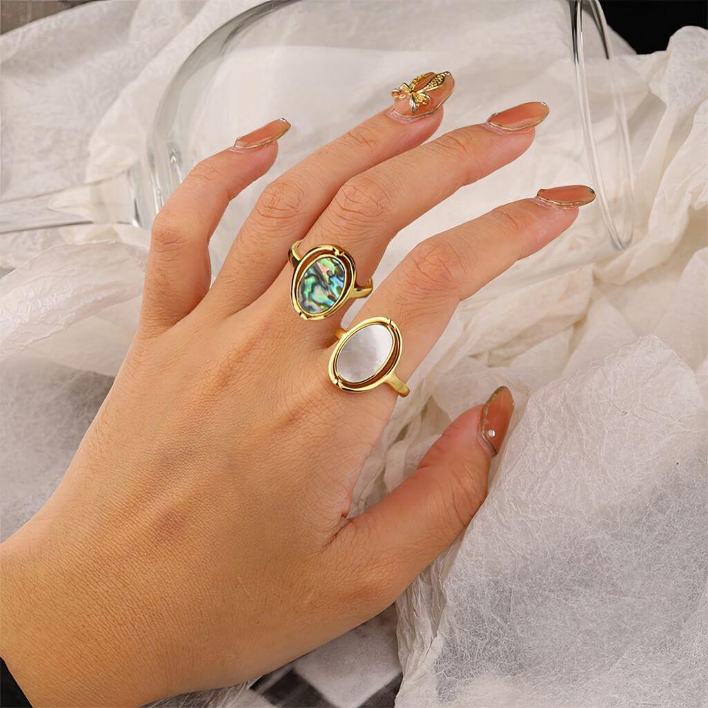 Two gold abalone rotating rings on grey background