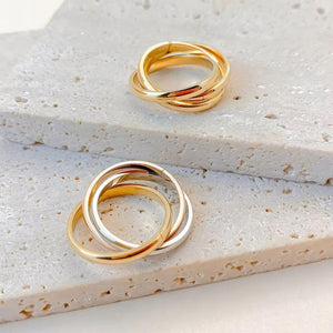 Two gold hoop earrings on a textured beige surface