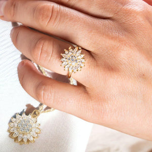 Woman's hand wearing fidget jewellery necklace and ring sunflower set on a white surface