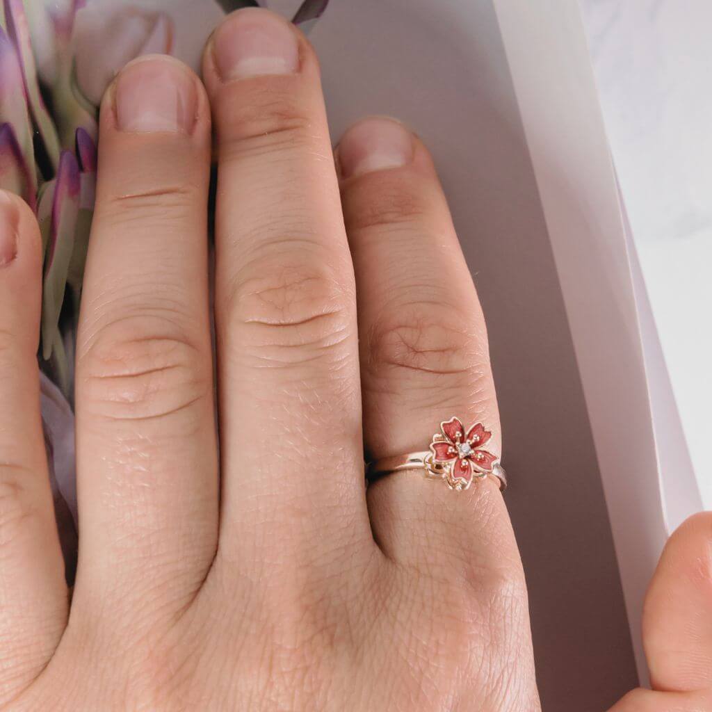 Woman's hand wearing a flower spinning ring on index finger  with a magazine cover surface