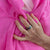 Woman's hand wearing gold and rainbow spinning rings Australia holding a pink shawl 