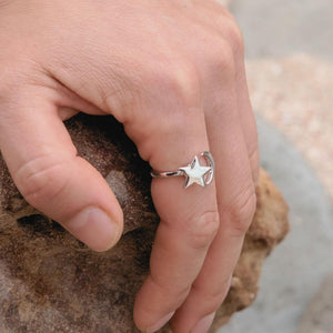 Woman's hand on a rock wearing a moon and star ring sterling silver
