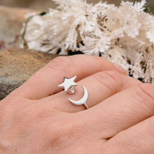 Woman's hand next to a sea sponge wearing an sterling silver crescent moon and star ring    