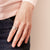 Woman's hand wearing a silver spinning ring for anxiety on black jeans