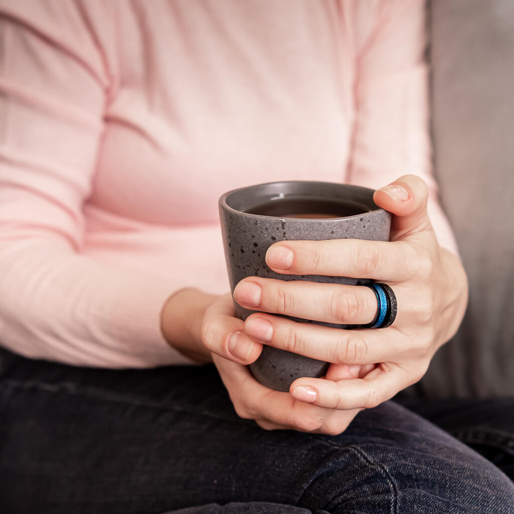 Woman holding a tea mug wearing sparkly anxiety rings Australia blue and black