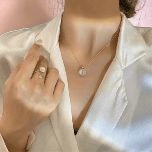 Woman in a white satin shirt wearing fidget jewellery for adults necklace and ring with opal spinning top