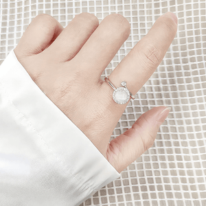 Woman in a white satin shirt wearing an opal fidget ring silver on her index finger