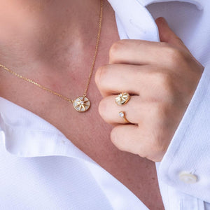 Woman in white shirt wearing a fidget jewellery set ring and necklace with a star spinning top