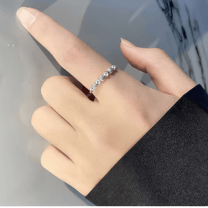 Hand with black sleeve wearing a sterling silver adjustable ring on the index finger
