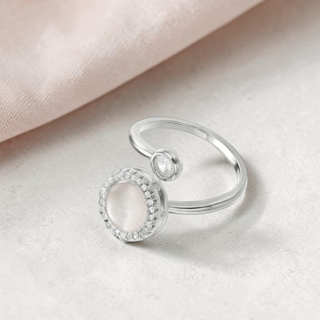 sterling silver adjustable anxiety ring with open band on soft neutral surface with blush fabric background