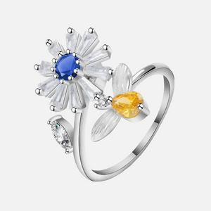 Rhodium plated 925 silver daisy spinner fidget ring with blue and amber cubic zirconia on white background