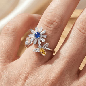 Close-up of rhodium plated 925 silver daisy spinner fidget ring with blue and amber stones worn on finger