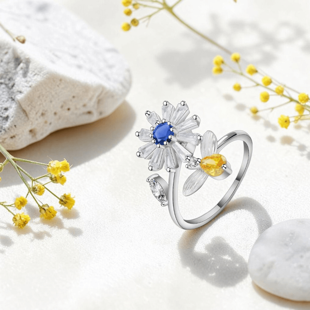 Silver daisy spinner anxiety ring with blue and yellow cubic zirconia styled with yellow wildflowers and white stones