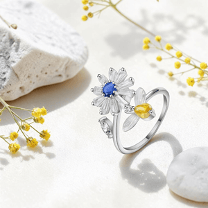 Silver daisy spinner anxiety ring with blue and yellow cubic zirconia styled with yellow wildflowers and white stones