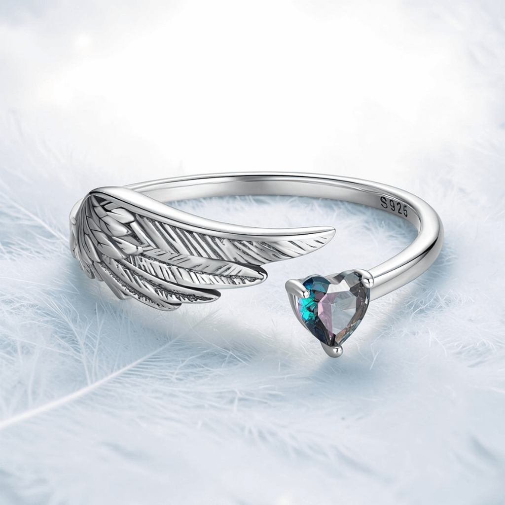 Sterling silver angel wing heart ring with S925 stamp and heart shaped gemstone on feather background