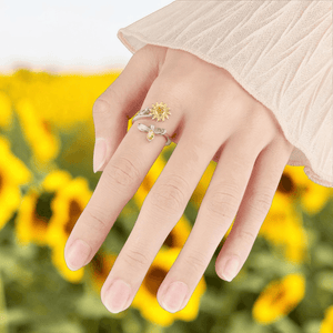 Hand wearing two-tone sunflower and bee spinner fidget ring in sunflower field