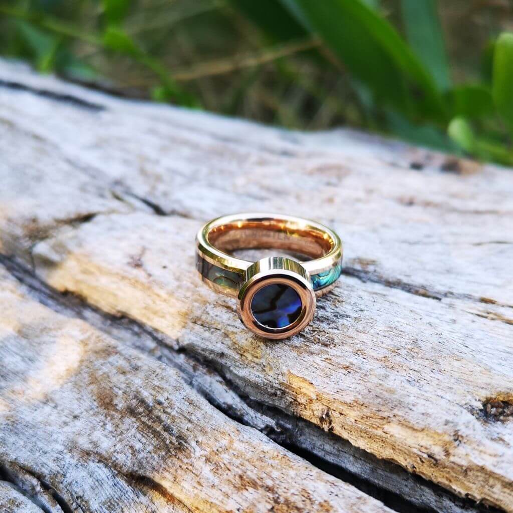 Abalone shell jewellery rose gold on a dry trunk