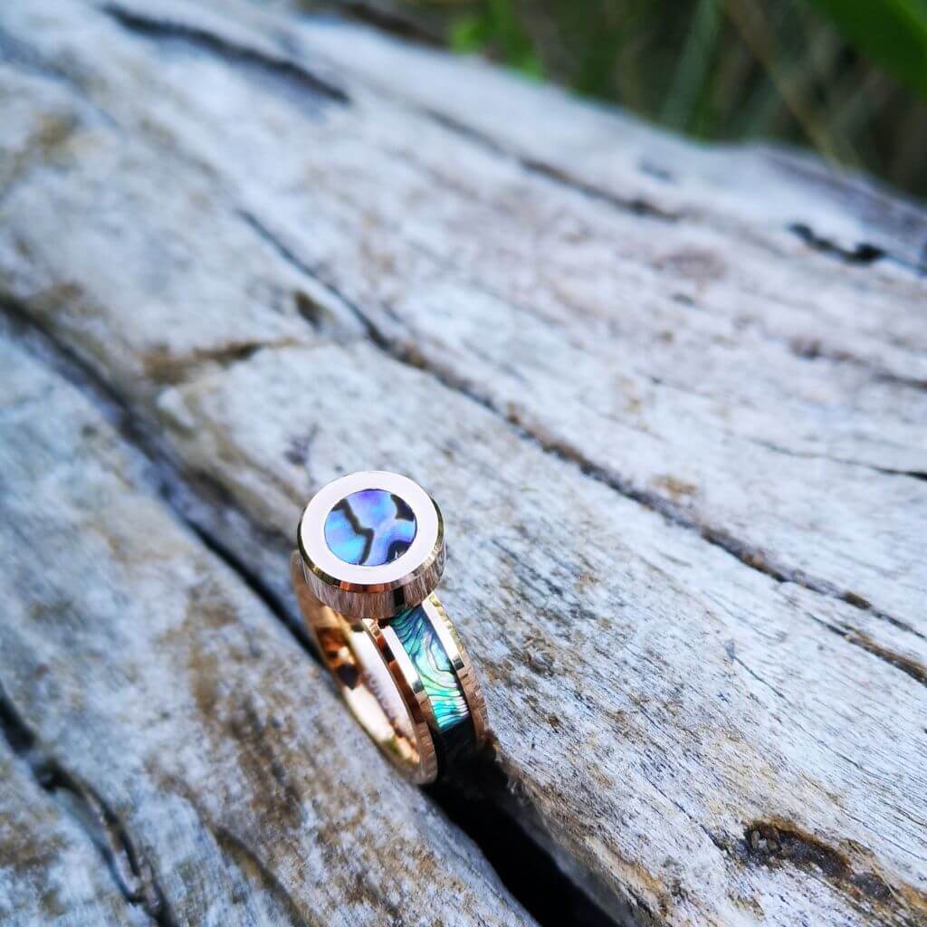 Abalone shell jewellery rose gold on a dry trunk