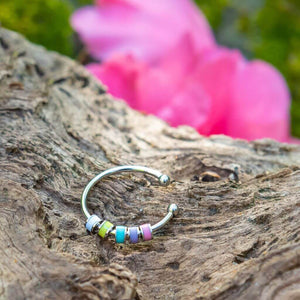 Colorful enamel ring with beads on a tree trunk