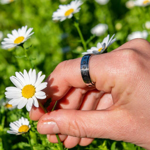 Hand wearing a calming ring with flowers picking a daisy