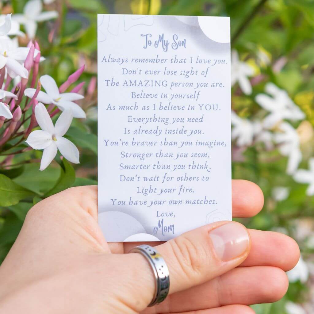 Hand wearing a moon and stars anti stress ring holding a message card for son