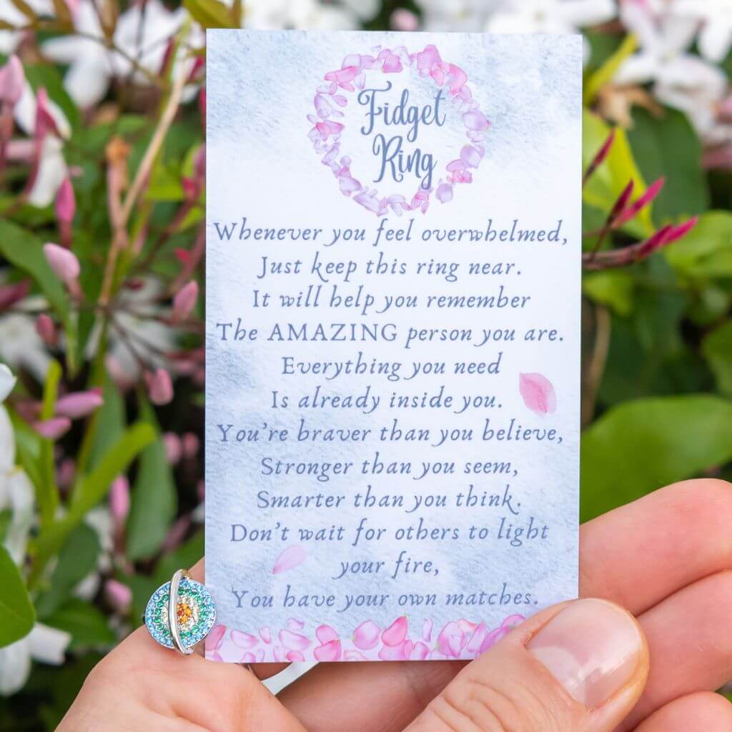 Woman's hand wearing a planet spinning anxiety ring holding a message card for son