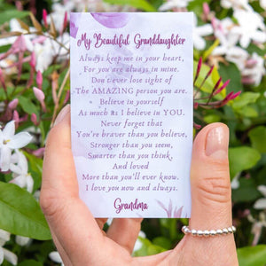 Woman's hand wearing a ring with beads holding a message card for granddaughter