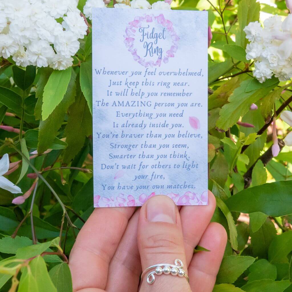 Woman's hand wearing a silver beaded adjustable ring holding a message card for friend